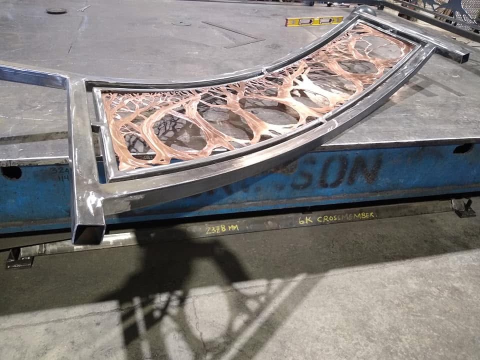 Curved copper tree branch panel being fabricated
