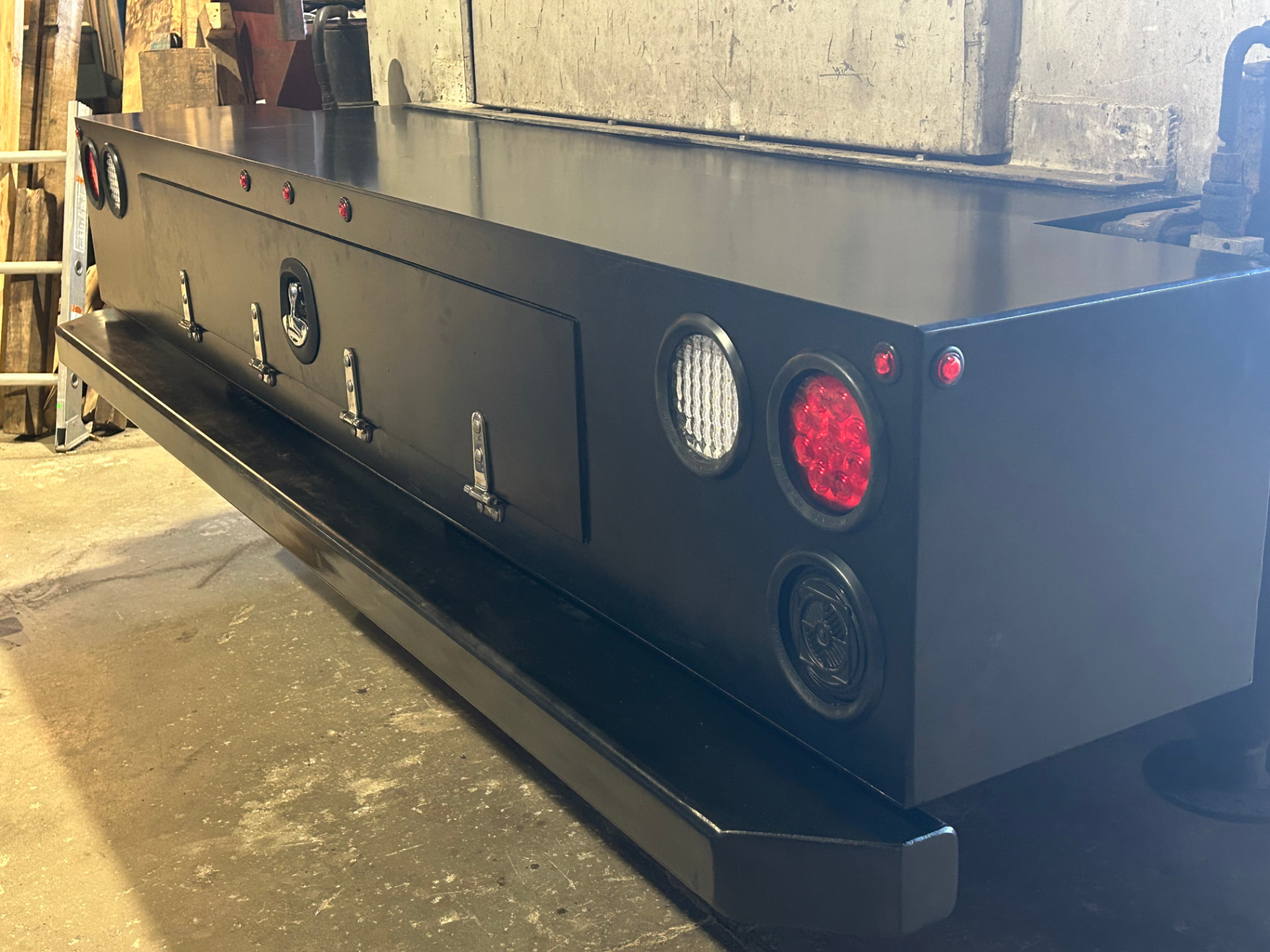 Custom fabricated black truck bumper with integrated lights in workshop